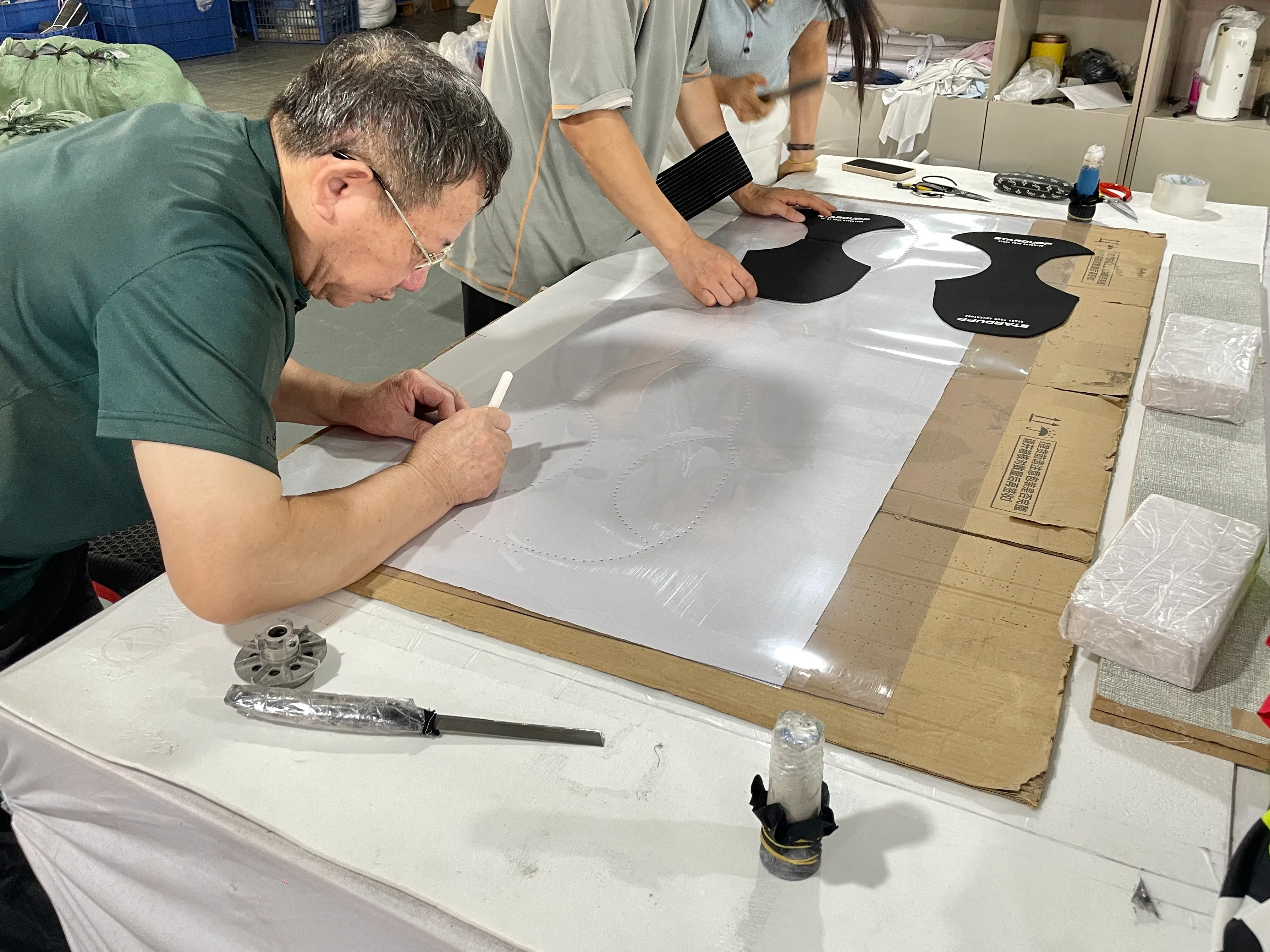 SHENOCHI team reviewing protective garment patterns on a factory worktable