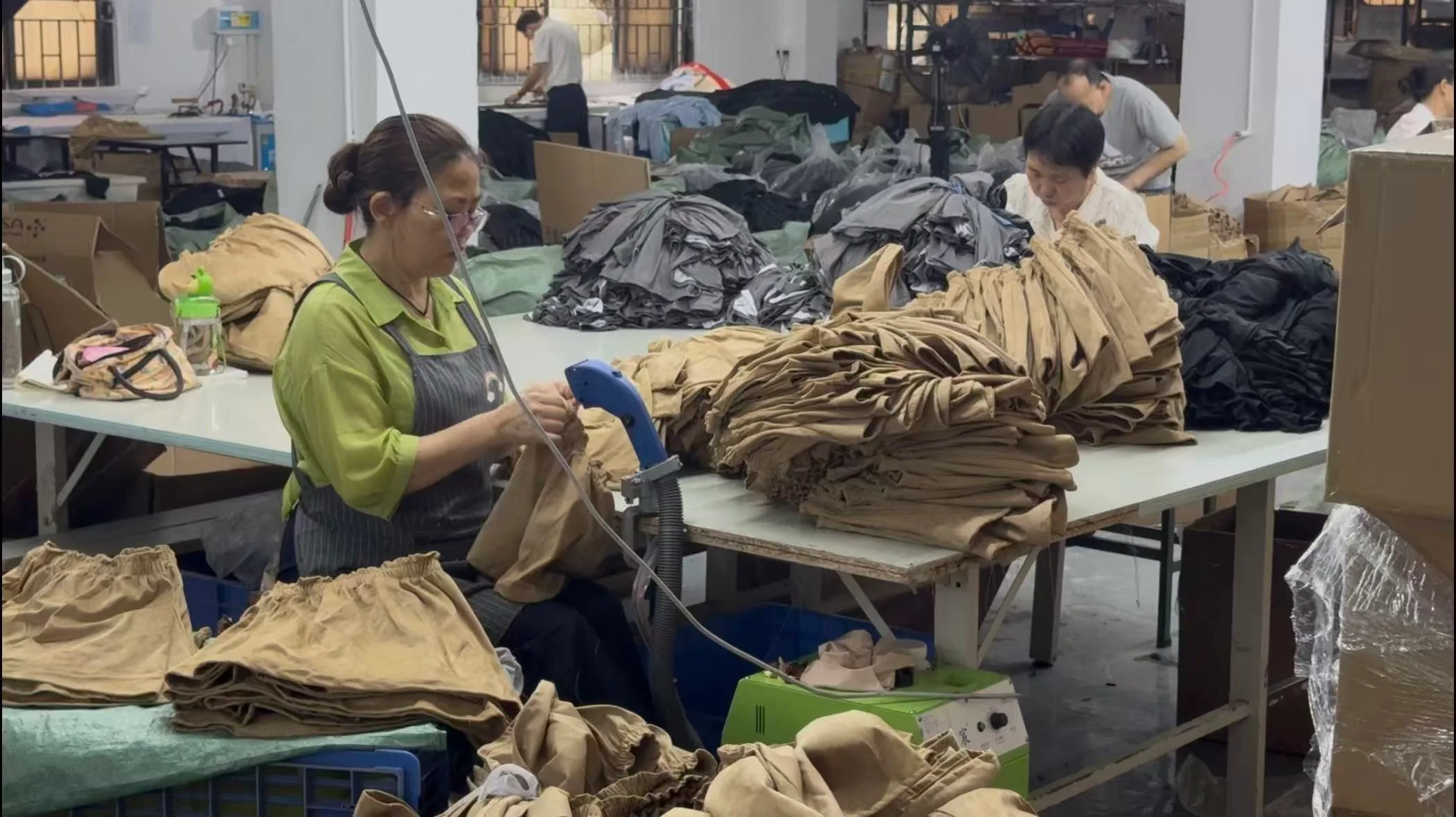 SHENOCHI factory team finishing tan garments at production worktables