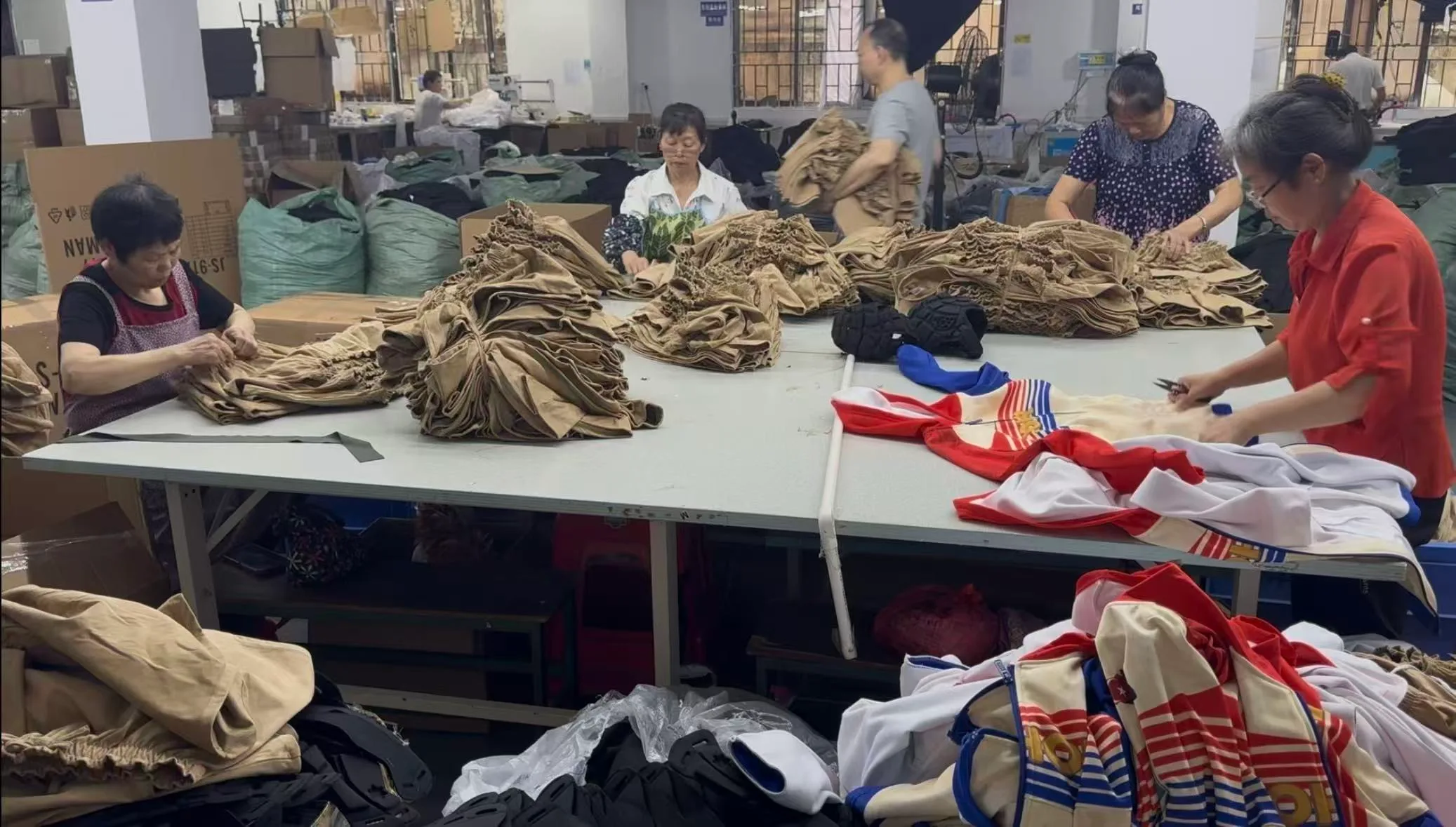 Factory team inspecting and trimming finished sports garments before packing